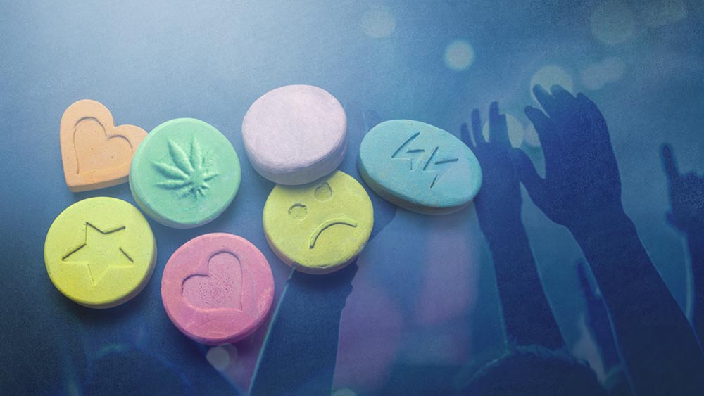 Different colored tablets that represent party drugs, and hands in the air that represent parties and dance clubs.