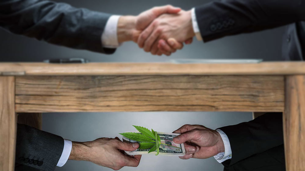 An image of two hands shaking, and below it one hand accepting money from the other to represent corruption.