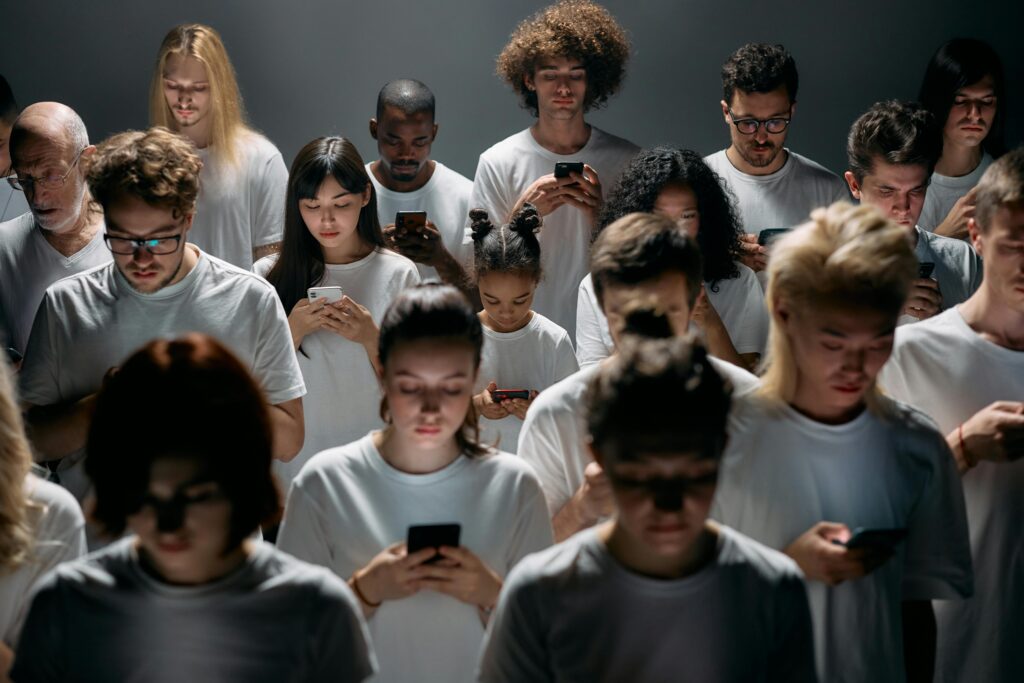 Group of people standing next to each other and all looking at their phones